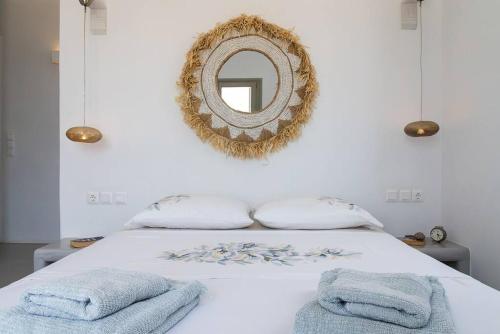 a bedroom with a white bed with a mirror on the wall at House of Harmony - Beachfront in Antiparos