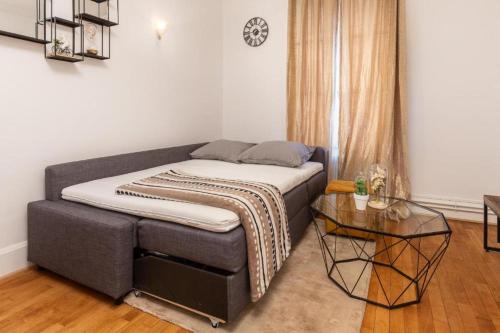 a bed in a room with a table at Élégance Parisienne : Confort & Connectivité avec Wifi & Netflix Inclus in Deuil-la-Barre