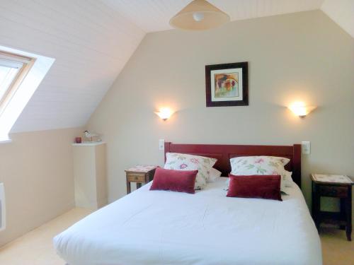 1 dormitorio con 1 cama blanca y 2 almohadas rojas en Maison sur jardin clos au calme à la campagne et proche des plages, en Mahalon