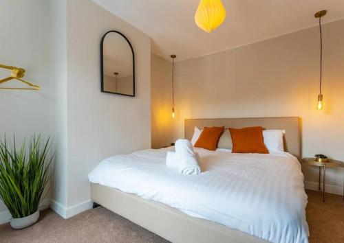 ein Schlafzimmer mit einem weißen Bett und orangefarbenen Kissen in der Unterkunft Modern & Comfortable Urban Home in Bournemouth