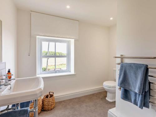 a bathroom with a sink and a toilet and a window at 2 Bed in Warkworth 93337 in Acklington