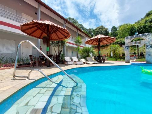 a swimming pool with two umbrellas in a house at Pousada Pompeia in Socorro