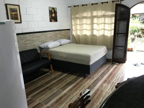 a small bedroom with a bed and a chair at Villaggio Miravela in Caraguatatuba