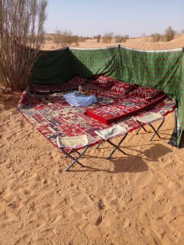 a picnic table on the sand in the desert at Private Camp25km-from DOUZ in Douz