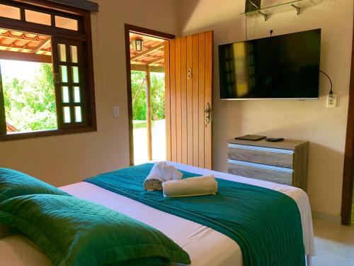 a bedroom with a bed with a flat screen tv at Pousada Recanto do Chalé Ltda in Macacos