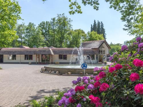 a fountain in front of a building with flowers at Holiday home in De Bult near Giethoorn Waters in De Bult
