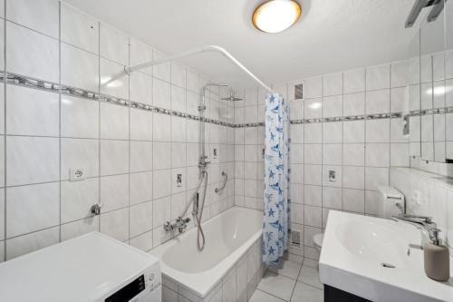 La salle de bains blanche est pourvue d'une baignoire et d'un lavabo. dans l'établissement Modernes 3 Zimmer Apartment mit Balkon, à Wuppertal