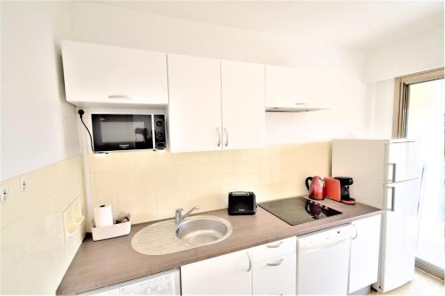 a kitchen with a sink and a microwave at L'ORANGERIE - Proche Mer - Terrasse - Parking privé - Clim in Roquebrune-Cap-Martin