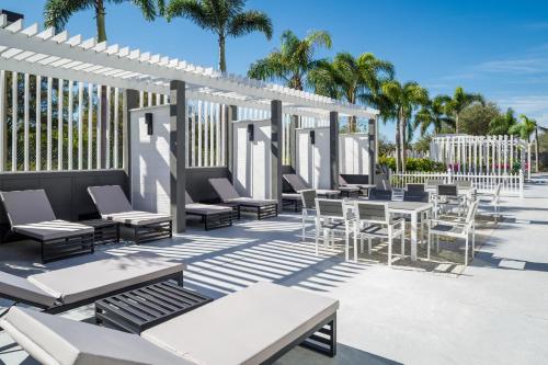 un patio con mesas, sillas y palmeras en DoubleTree by Hilton Sarasota Bradenton Airport en Sarasota