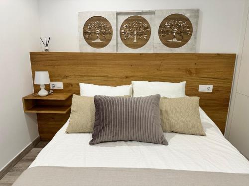 1 dormitorio con cama blanca y cabecero de madera en Apartamento Lux Santiago, en Santiago de Compostela