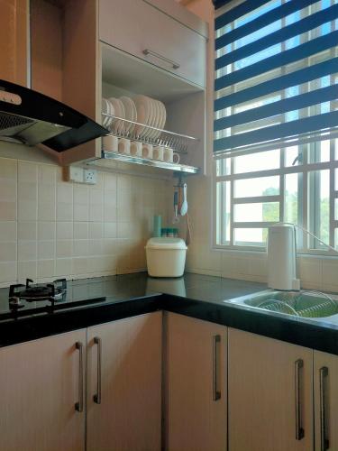 eine Küche mit einer Theke, einem Waschbecken und einem Fenster in der Unterkunft COZY CR Guesthouse Nilai Pajam with Self Check-In in Nilai
