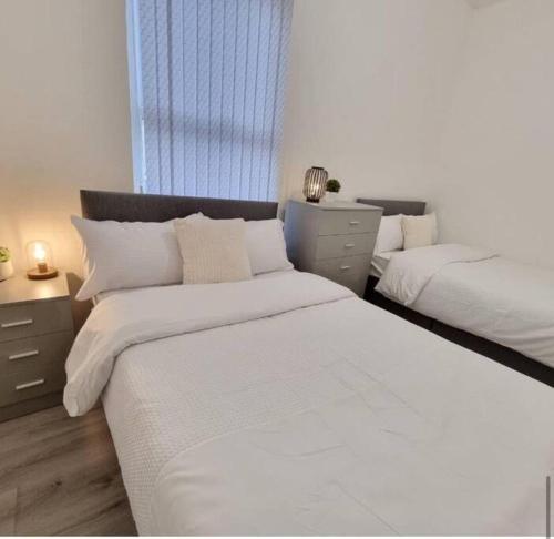 a white bedroom with two beds and a window at London Central Luxury Stay in London