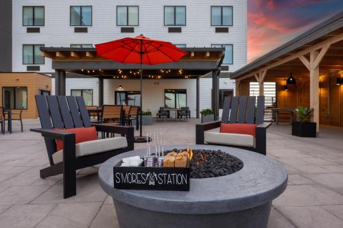 a patio with two chairs and a fire pit with an umbrella at The Winslow - Winslow, AZ in Winslow