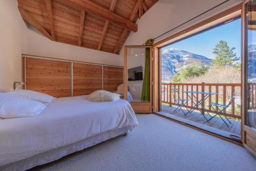 a bedroom with a bed and a balcony with a view at Chalet Snowbird 5 étoiles, Serre-Chevalier in La Salle-les-Alpes