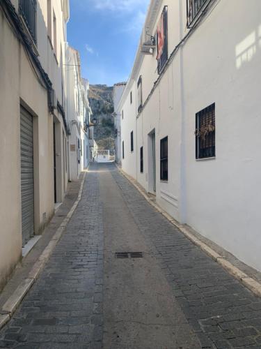 an alley with white buildings and a cobblestone street at La Cueva in Zuheros