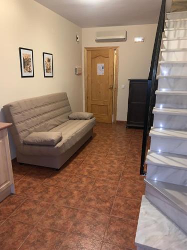 a living room with a couch and a staircase at La Cueva in Zuheros