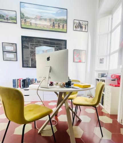 an apple computer on a table in a room with yellow chairs at Hackert Art Room Apartment in Caserta