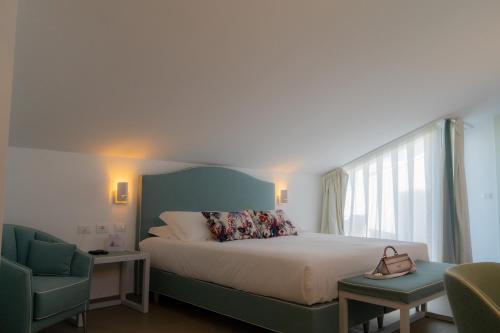 a bedroom with a bed with a green headboard and two chairs at Seaside Hotel in Capo dʼOrlando