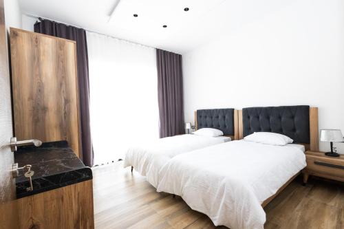 two beds in a bedroom with white sheets at Harmonija SPA RESORT in Vrdnik