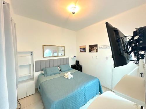 - une chambre avec un lit bleu et une télévision à écran plat dans l'établissement Studio'S Bartho Leblon, à Rio de Janeiro