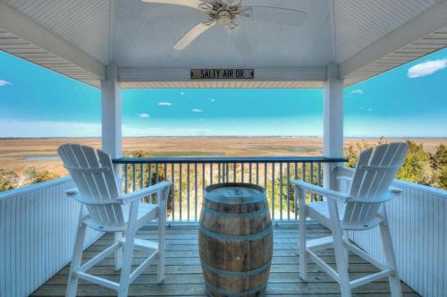 two chairs and a barrel on a porch with a view at A-Frameable Moment in Oak Island