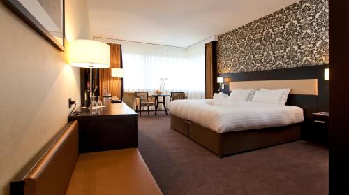 a hotel room with a large bed and a desk at Mercure Antwerp City South in Antwerp