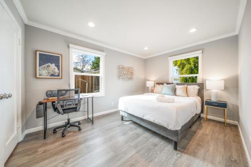 a bedroom with a bed and a desk and two windows at 4BR Lux Los Gatos Home: Style & Comfy in Los Gatos