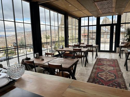 a restaurant with tables and chairs and large windows at Turan Cappadocia Cave in Goreme