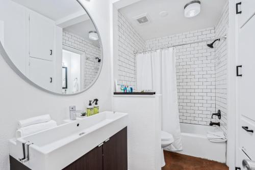 a white bathroom with a sink and a mirror at SoCo Oasis Retreat: Relax in Comfort and Style in Austin