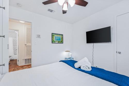 a bedroom with a bed with a ceiling fan and a tv at SoCo Oasis Retreat: Relax in Comfort and Style in Austin