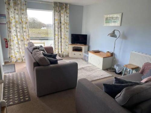 uma sala de estar com dois sofás e uma televisão em Manorcombe 19 em Gunnislake