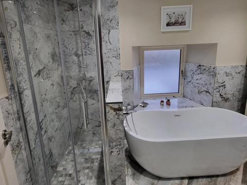 y baño con bañera blanca y ducha. en Blackriver House, en Shruthair