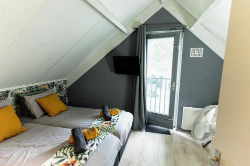 a attic room with two beds and a window at Rumah Senang Ewijk met royale tuin en hottub in Ewijk