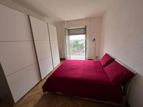 Cama roja en habitación con ventana en Milan Apartment - Città Studi: 75mq for you en Milán