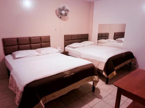 Habitación con 2 camas y reloj en la pared en Hostal La Dulce Vida, en Trujillo