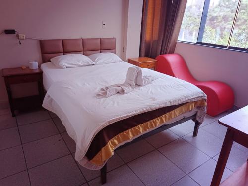 1 dormitorio con 1 cama y 1 silla roja en Hostal La Dulce Vida, en Trujillo