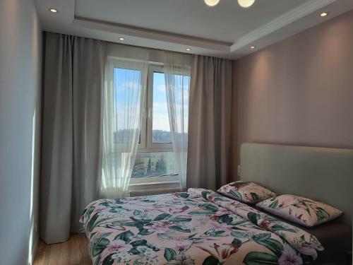 a bedroom with a bed and a large window at Nowy apartament przy ulicy Kurpiowskiej blisko centrum miasta in Siedlce