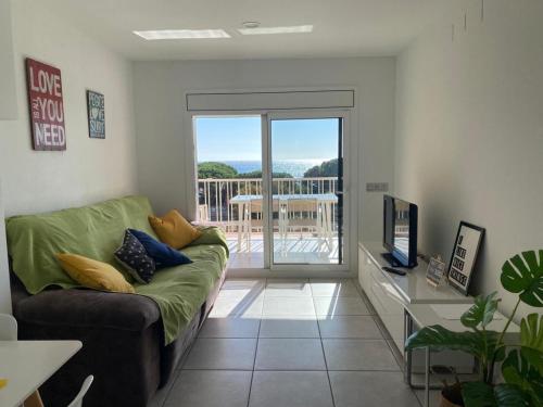 a living room with a couch and a sliding glass door at Apartamento frente al mar con piscina in Malgrat de Mar