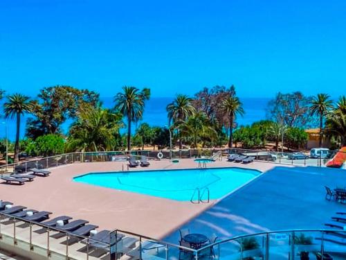 a swimming pool with chairs and the ocean in the background at Ocean View Santa Monica Three-Bedroom Apartment in Los Angeles