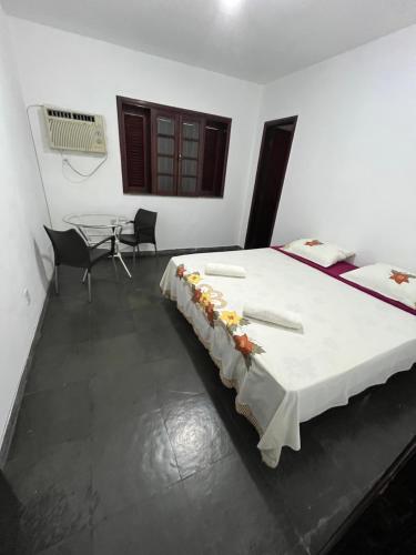 a bedroom with a bed with a table and chairs at Hostel e Restaurante Dona Lu in Itaperuna