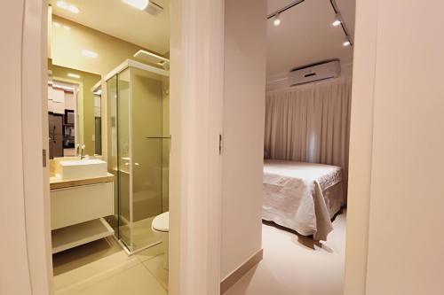 een slaapkamer met een bed en een badkamer met een wastafel bij JPN87 - Duplex em condomínio fechado próx. à praia in Natal