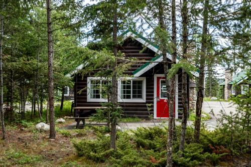 a log cabin with a red door in the woods at Pine Bungalows in Jasper