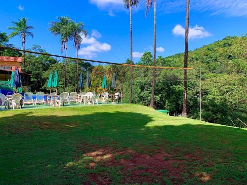 a large yard with palm trees and a net at Pousada Recanto do Chalé Ltda in Macacos