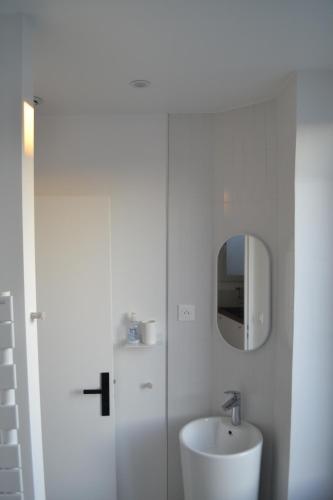 W białej łazience znajduje się umywalka i lustro. w obiekcie Stunning last floor - Up to 5 P w Paryżu