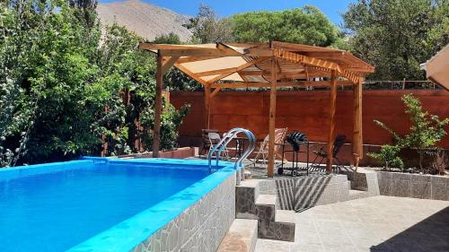 a swimming pool with a wooden pergola next to at Refugio Renacer in Pisco Elqui