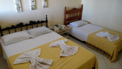 two beds in a room with towels on them at Pousada Zekas in Jacumã