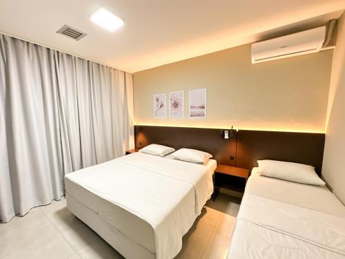 a hotel room with two beds and a window at Presto Hotel in Blumenau