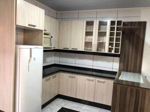 a kitchen with wooden cabinets and a white refrigerator at Casa com AR COND. em todos os comodos mobiliada in Cascavel