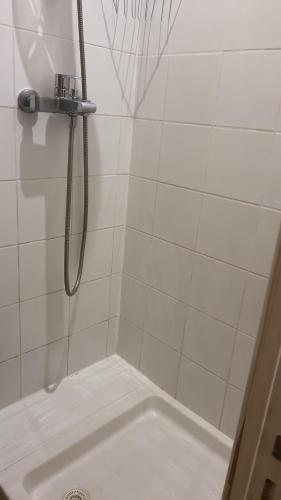 uma casa de banho com um chuveiro e uma parede de azulejos brancos. em Cosy Homestay Antony Parking libre em Antony