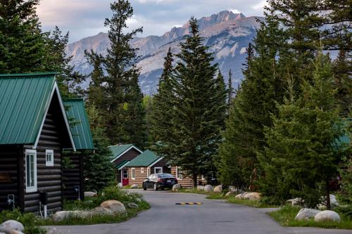 a row of log homes with mountains in the background at Pine Bungalows in Jasper